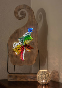 Glaslampe aus geschnittenem Buntglas, umrahmt von einem aufwendig verarbeiteten Rahme, verbunden mit einem Flachstahl auf einem Holzsockel.